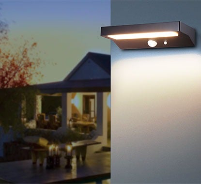 Casa com iluminação exterior e um candeeiro exterior solar que poupa energia e tem a mesma intensidade de luz